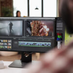 Male videographer editing video montage on post production software, working on computer. Creating movie content with color grading, edit creative multimedia film footage on app.